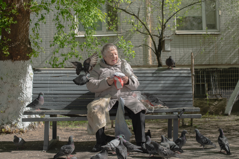 The old woman is feeding the birds